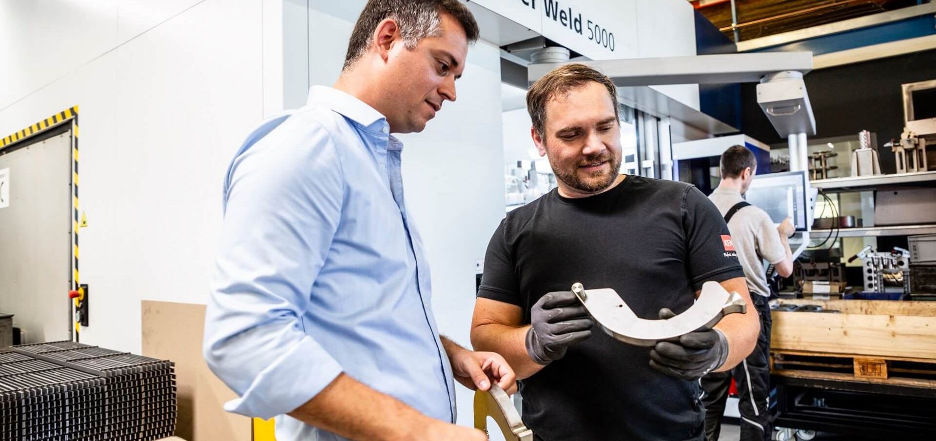 Gemeinsames Betrachten eines Bauteils in Produktionshalle