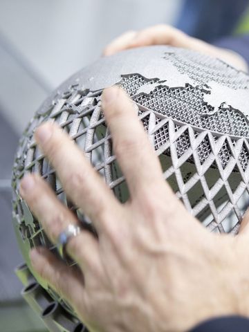 Menschen umfassen Weltkugel aus Metall