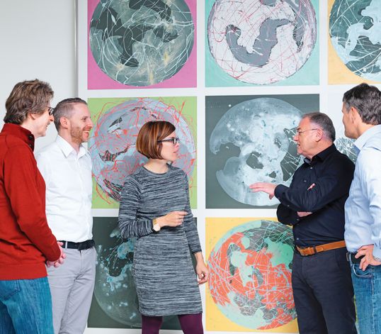 TRUMPF employees talking in front of a piece of painting