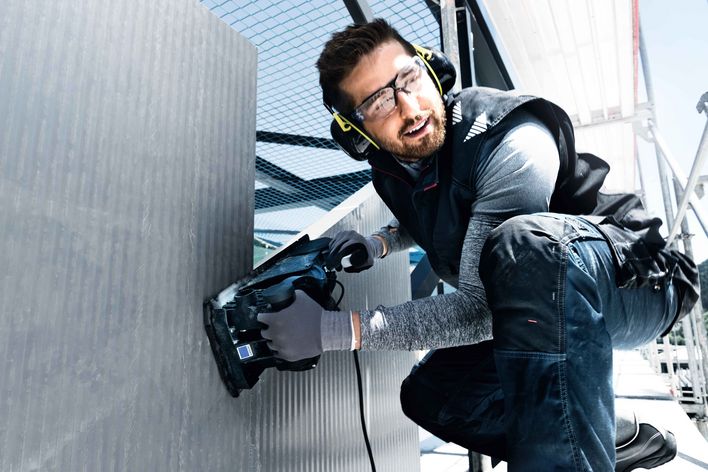 Un homme avec ses protections de travail (lunettes, gants, protection auditive)